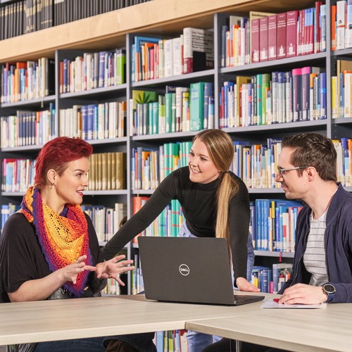 Zwei Frauen und ein Mann diskutieren in der Bibliothek