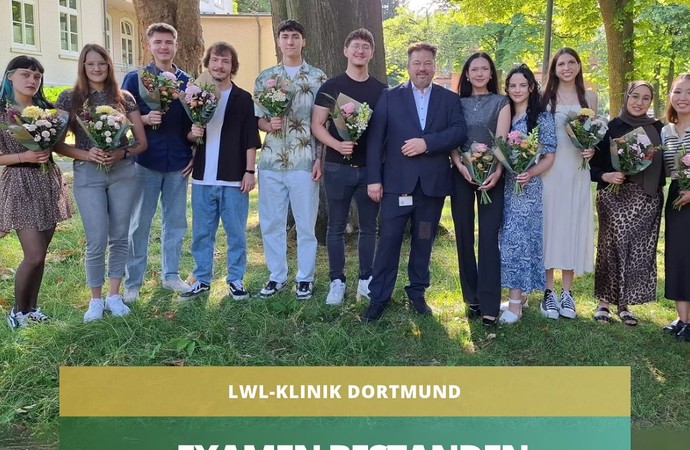 11Pflegeschülerinnen und Schüler präsentieren ihr Abschusszertifikat. Sie stehen unter einer großen Platane.